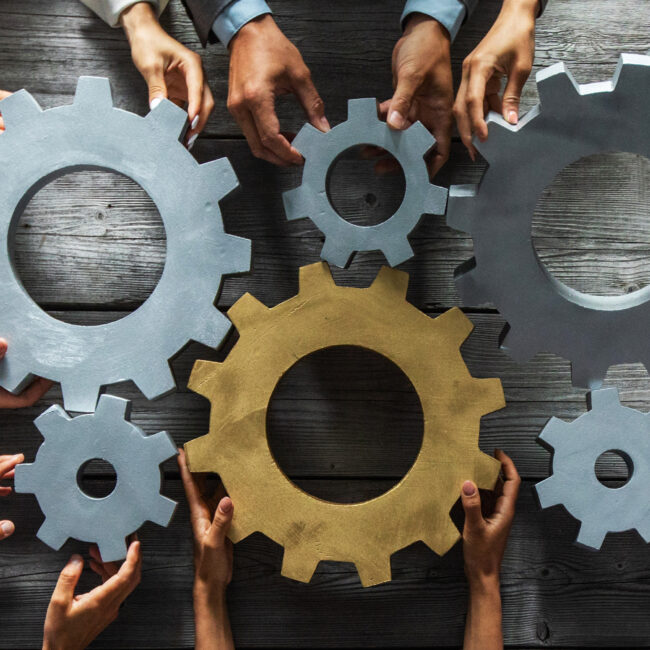 Business Team Members holding gears that fit together to work